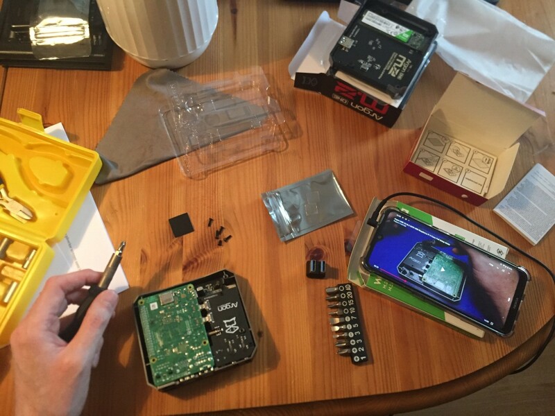En bild på ett Raspberry Pi 4-kretskort med tillbehör på ett bord plus en smartphone med en guide på YouTube.