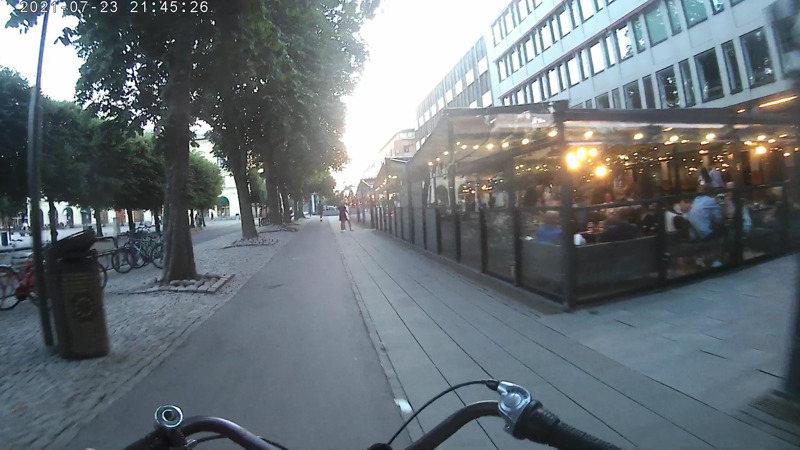 Skärmdump från en actionkamera, där bloggägaren cyklar förbi ett gäng uteserveringar i centrala Karlstad.