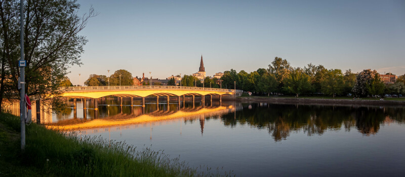 Vi över Tingvallabron i Karlstad med Domkyrkan i mitten. Bron lyser upp av solnedgången och Klarälven ligger spegelblank