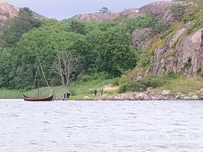 Kraftigt inzoomad bild på 3 personer som ska bada. 2 av dom är utklädda i vikingastil och har gått iland från en vikingabåt.
